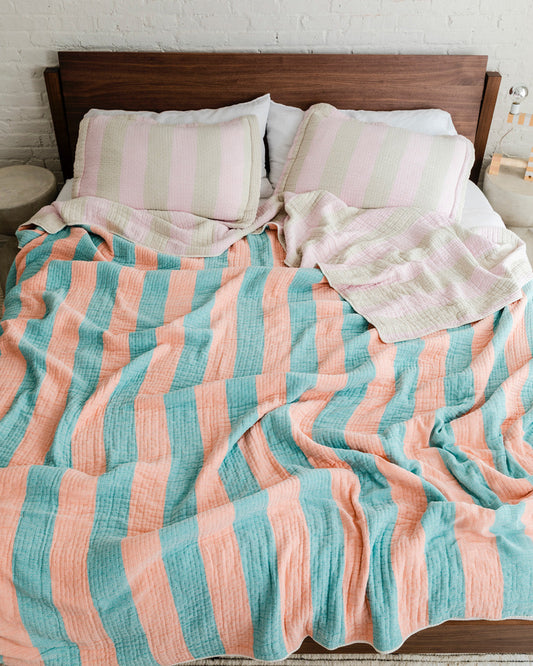 Dusen Dusen Warm Stripe Coverlet Set in reversible stripe colorways. Pink and beige stripes on one side, orange and green stripes on the other side. Woven matelassé coverlet with an inner layer of insulation for a quilted effect. Stonewashed, with an extra soft and gauzy hand feel. 100% cotton shell, polyester fill. Machine wash cold and tumble dry low. Made in Portugal.; Ever heard of a blanket being warm? Yeah, thought so. We actually invented that!